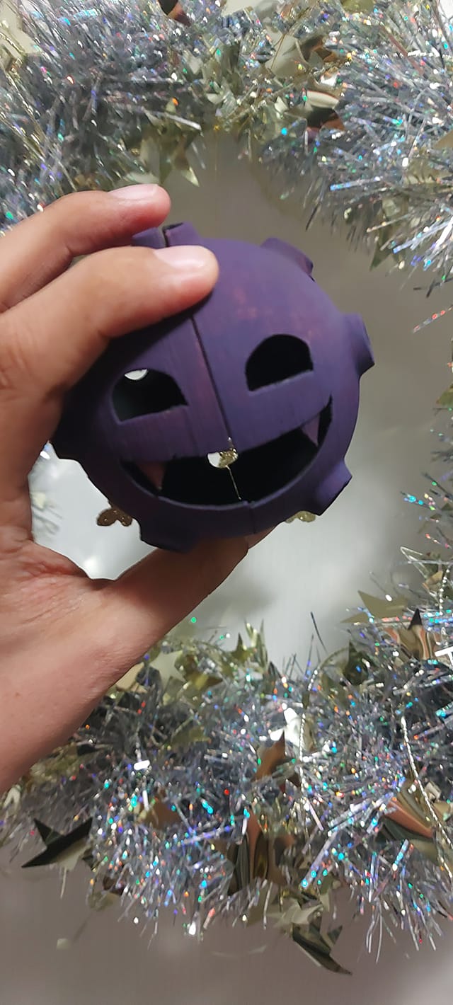 A 3D printed Koffing held in front of the wreath from before, it is mostly painted